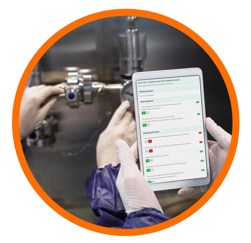 Factory worker using a tablet to complete digital cleaning and inspection checks in a food production environment.