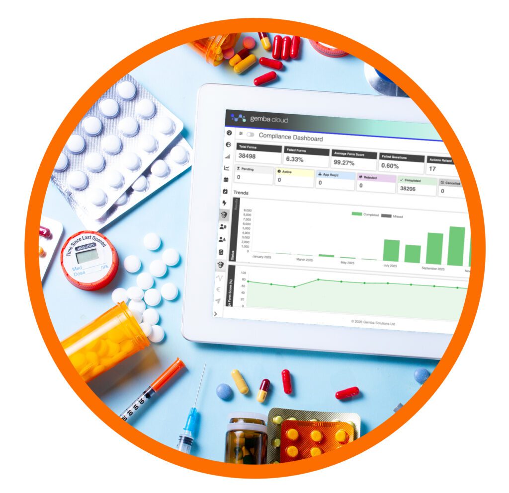 Tablet displaying a pharmaceutical compliance dashboard surrounded by medicines, blister packs and medical supplies, representing digital quality and compliance management.