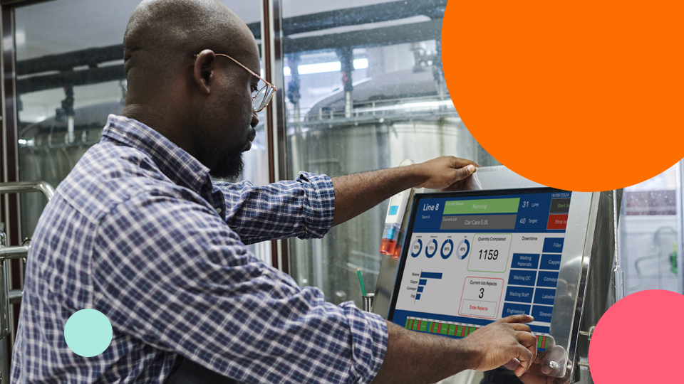 Manufacturing operator using a digital production monitoring screen to review workforce and operational performance data.